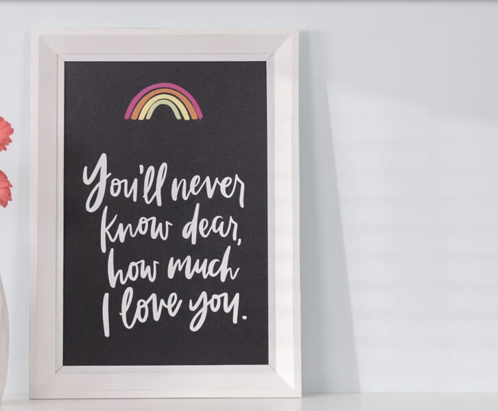 You'll Never Know Dear Transfer design on 12x18 chalkboard next to vase of pink daisies