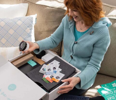 Winter 2021 Starter Kit lifestyle image showing Designer sitting on sofa with starter kit box.
