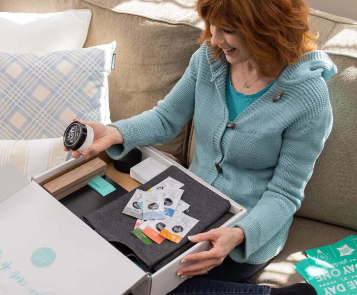 Winter 2021 Starter Kit lifestyle image showing Designer sitting on sofa with starter kit box.